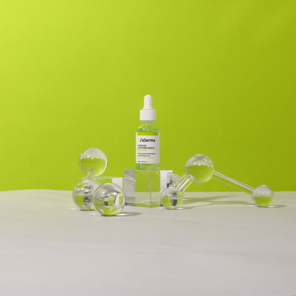 Skincare products including a dropper bottle and roller on a green background