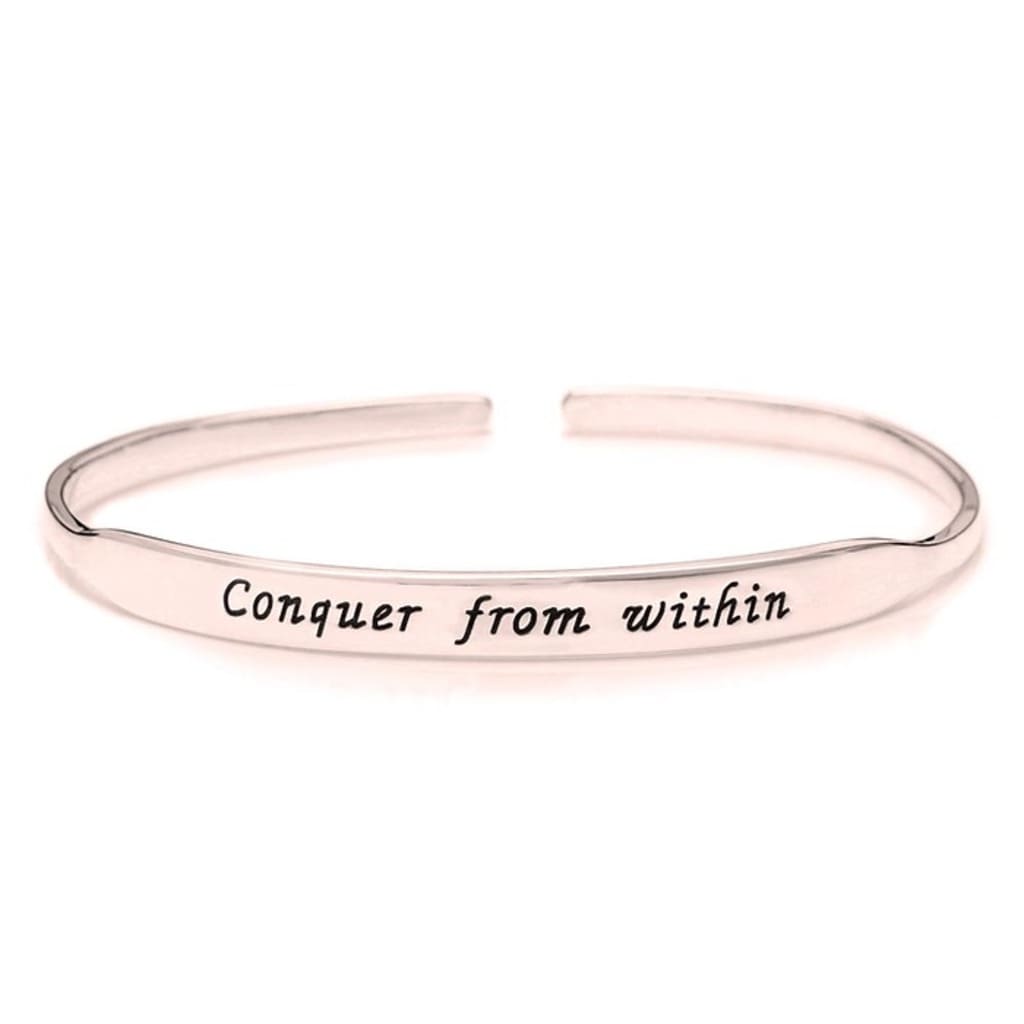 Rose gold bracelet with 'Conquer from within' engraving on a white background