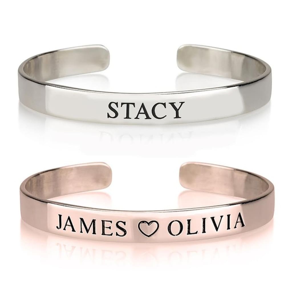 Two silver bangles with engraved names on a white background