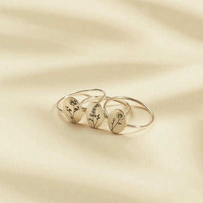 Three gold rings with floral designs on a beige background