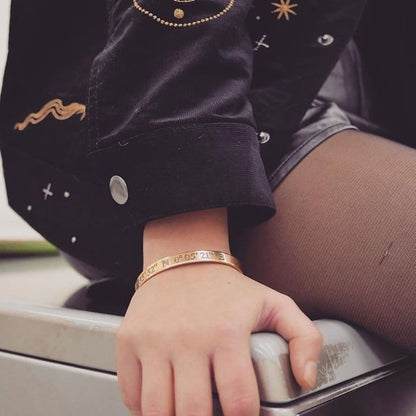 Person wearing a gold bracelet on a car's dashboard