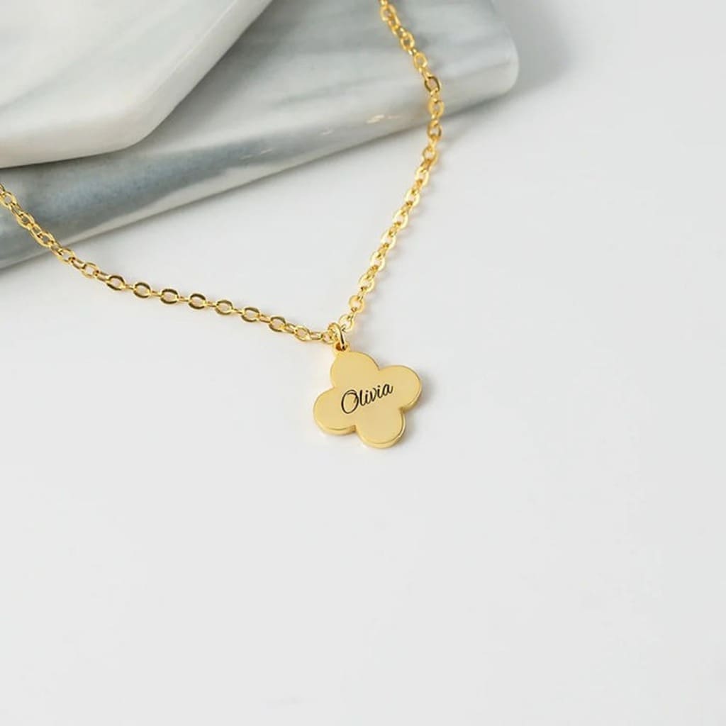Gold necklace with a clover-shaped pendant on a white background