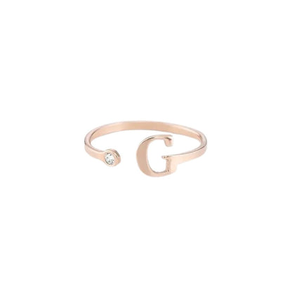 Rose gold bracelet with letter 'G' and small gemstone on a white background