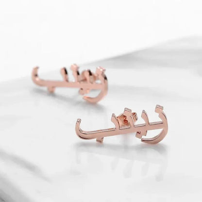 Rose gold earrings with Arabic script on a white background
