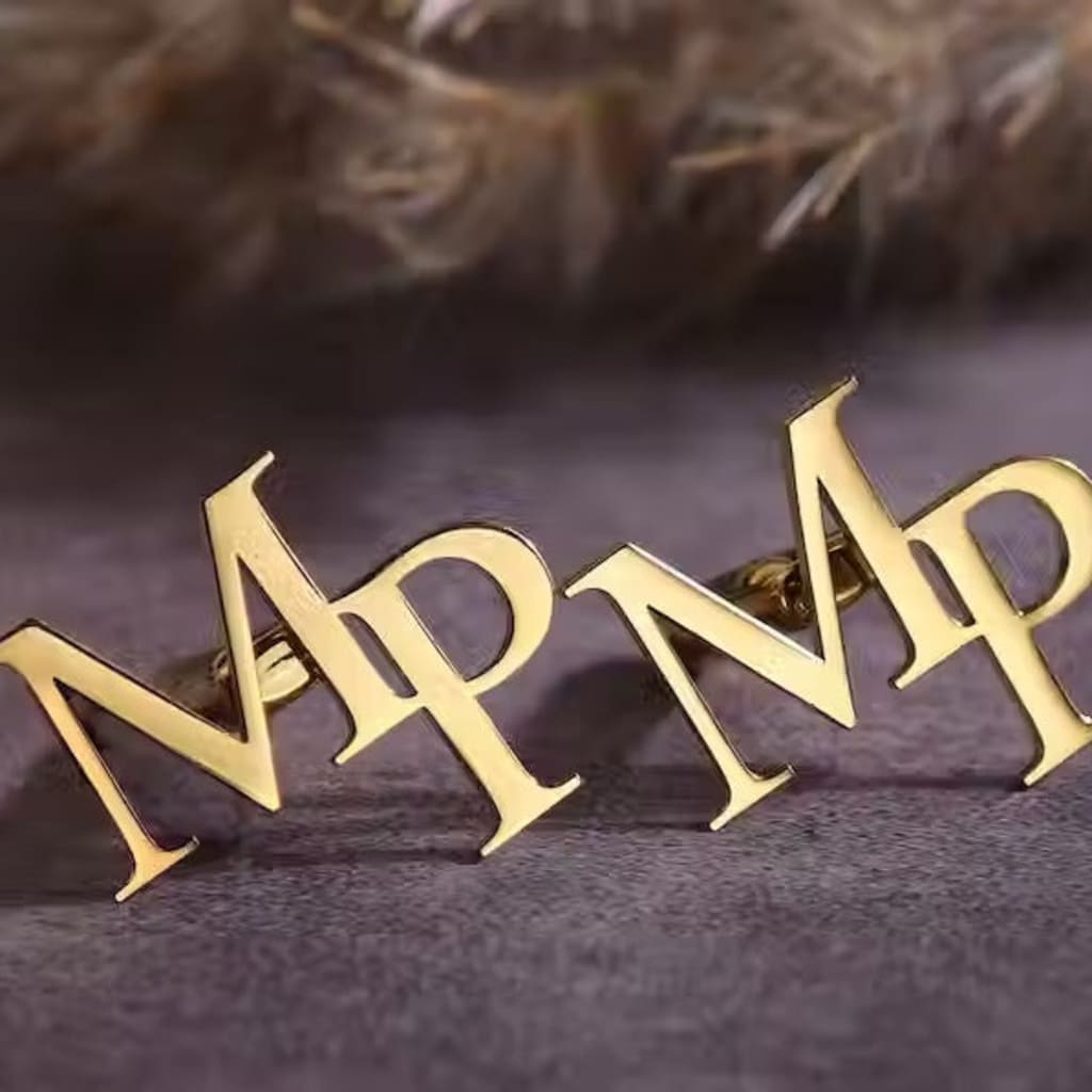 Gold letter 'P' brooch on a dark textured background