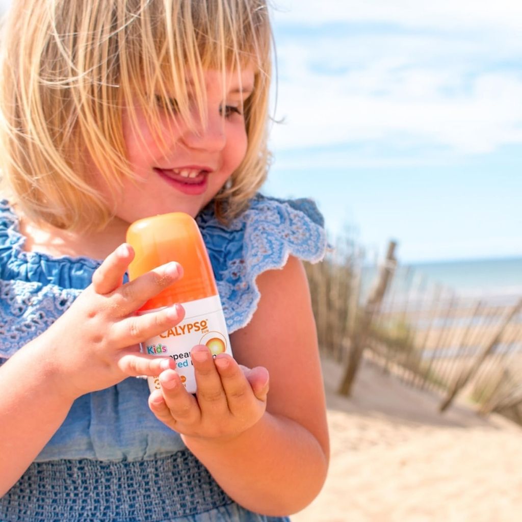 Child holding a container of Ellypso at the beach