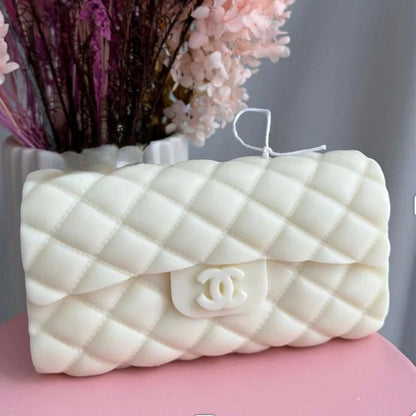 White quilted Chanel handbag on a pink surface with flowers in the background