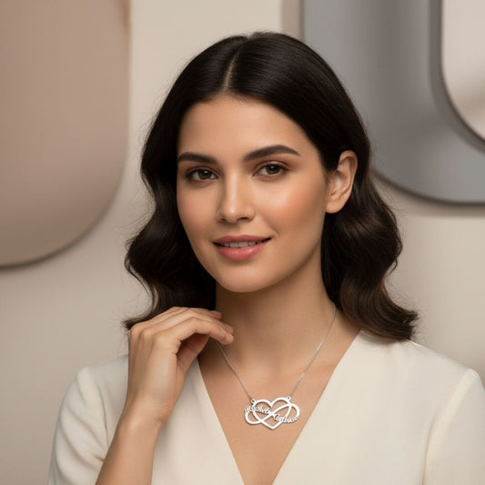 Woman wearing a silver necklace with a heart design against a neutral background