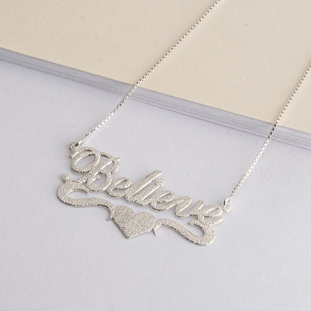 Silver necklace with 'Believe' pendant on a light background