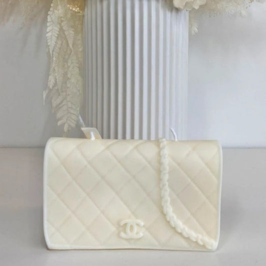 White quilted handbag with Chanel logo on a light gray surface.