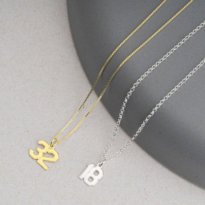 Two necklaces with unique pendants on a neutral background