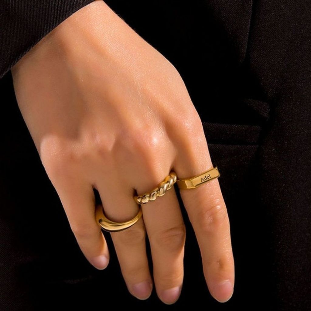 Hand wearing two gold rings with a black background