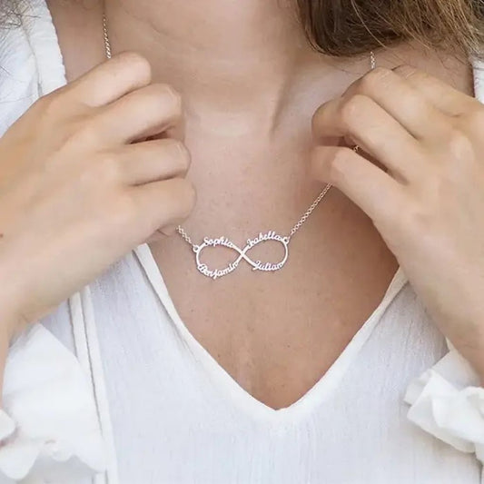 Person wearing a silver infinity necklace with a white top