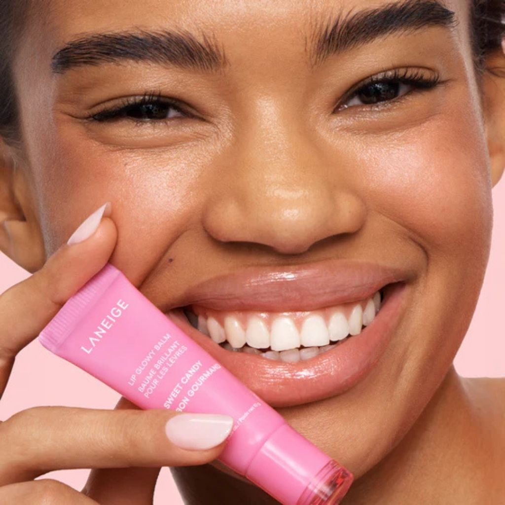 Woman holding a pink Laneige product against a pink background