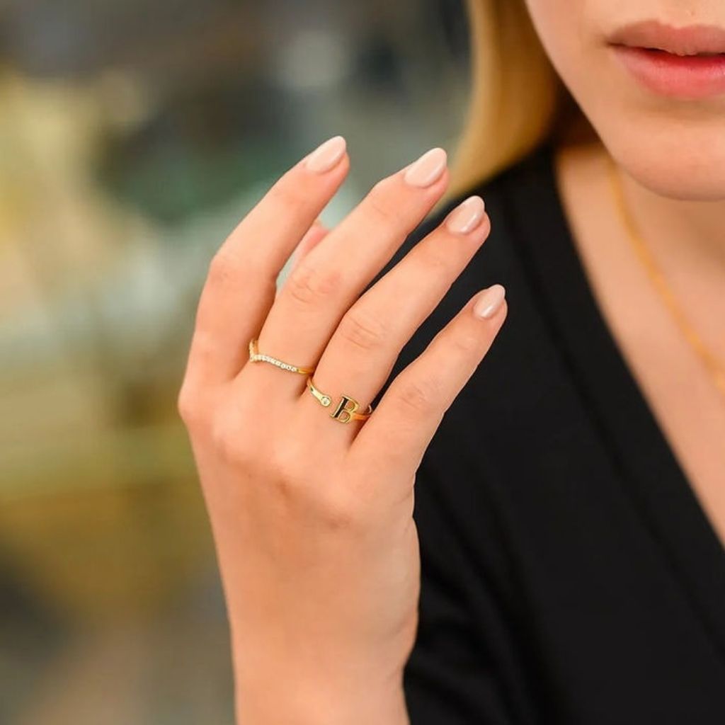 Close-up of a hand wearing two gold rings with a blurred background