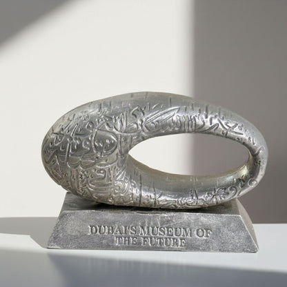 Metallic sculpture with engraved design on a stand, labeled 'Dubai Museum of the Future'.