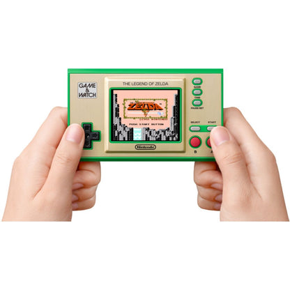 Handheld gaming console with 'The Legend of Zelda' display held by two hands on a white background