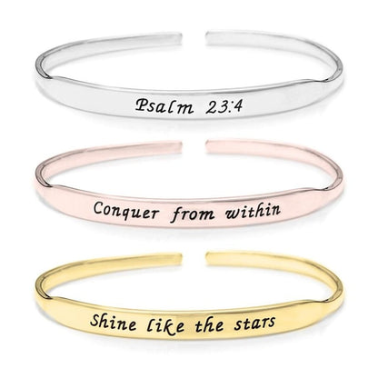 Three gold, rose gold, and silver bangles with engraved text on a white background