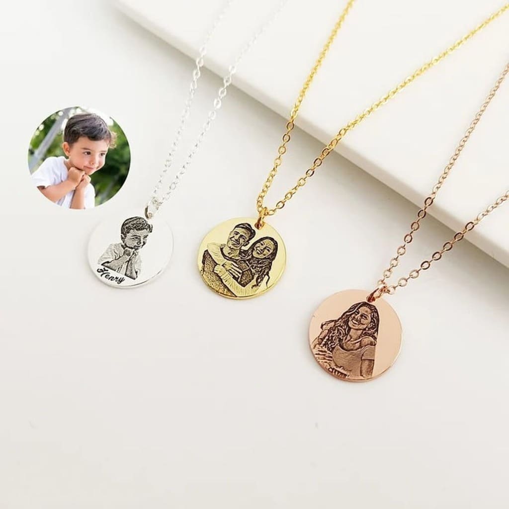 Three necklaces with engraved images on a white surface