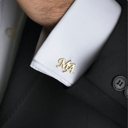 Close-up of a black suit with white cufflinks featuring initials 'MA'.