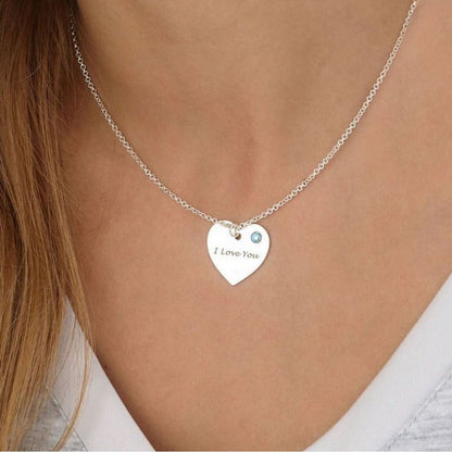 Silver necklace with a heart-shaped 'I Love You' pendant on a person wearing a white top.