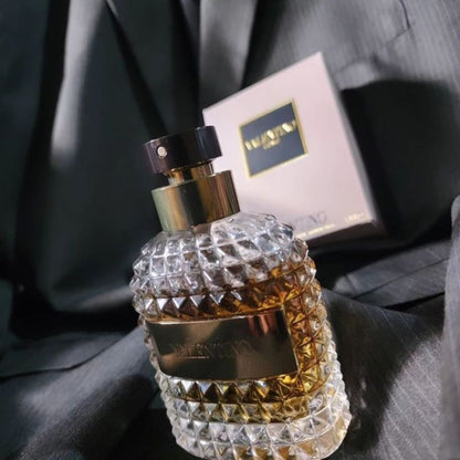Perfume bottle with diamond pattern and gold accents on a dark fabric background