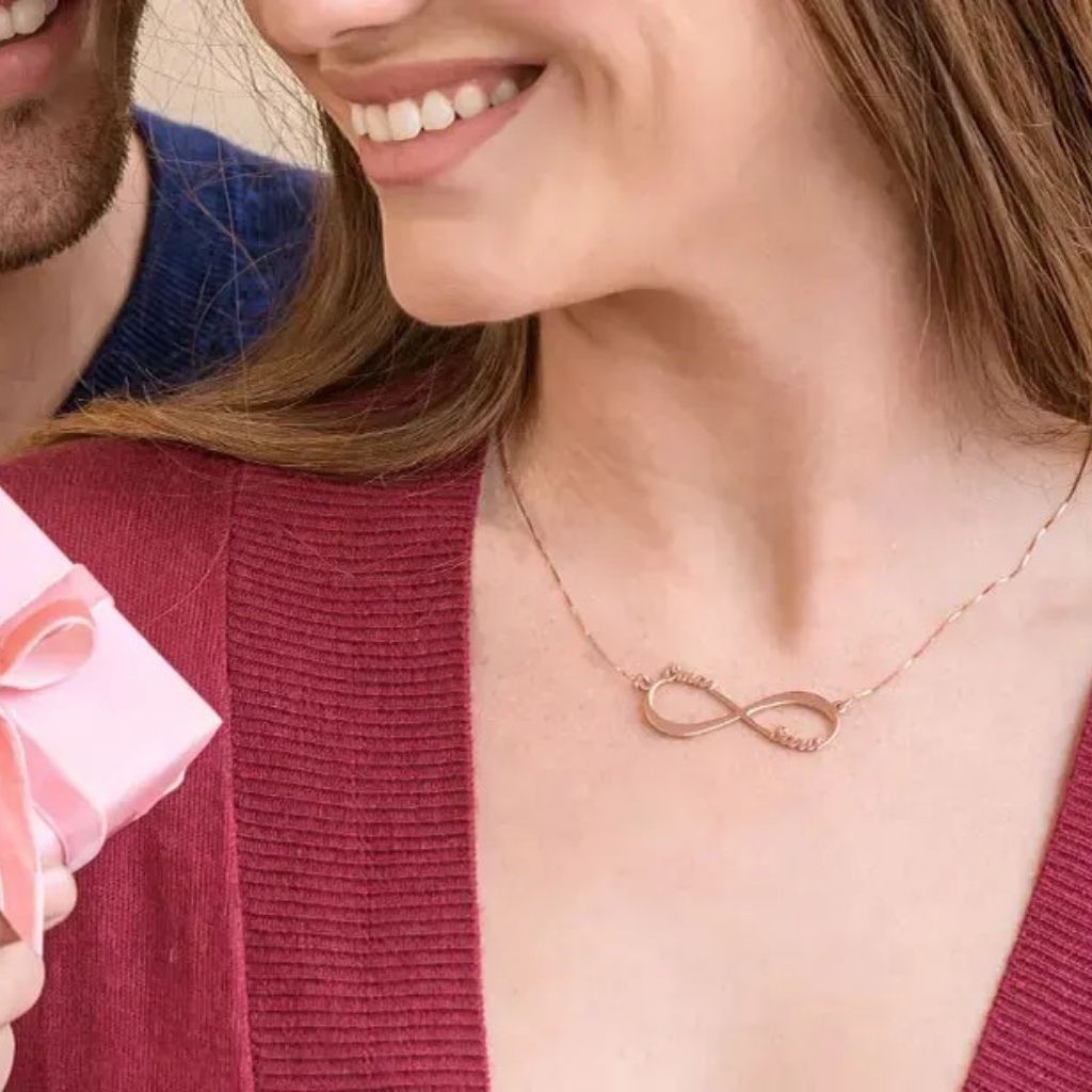 Woman wearing a gold infinity necklace with a blurred background