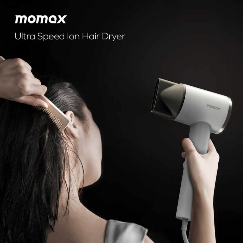 Person using a Momax ultra speed ion hair dryer on a dark background