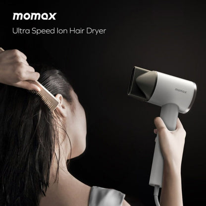 Person using a Momax ultra speed ion hair dryer on a dark background