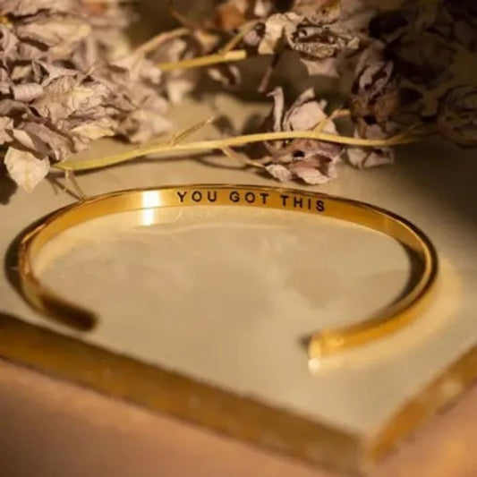 Gold bracelet with 'YOU GOT THIS' text on a light background