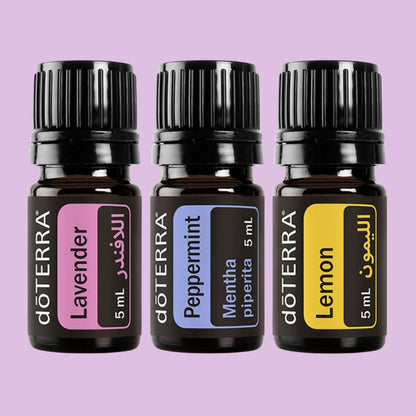 Three doTERRA essential oil bottles labeled Lavender, Peppermint, and Lemon on a purple background.