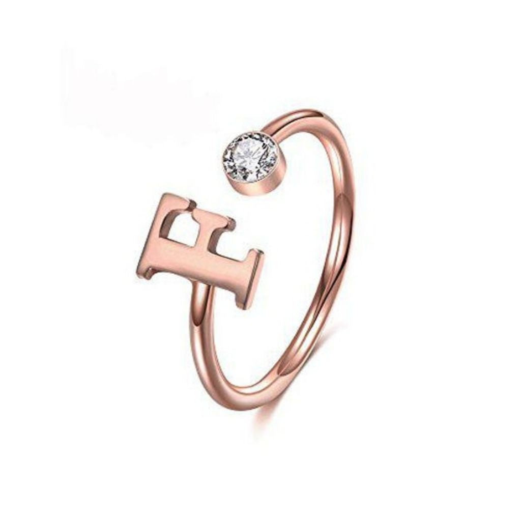 Rose gold ring with letter 'H' and clear gemstone on a white background