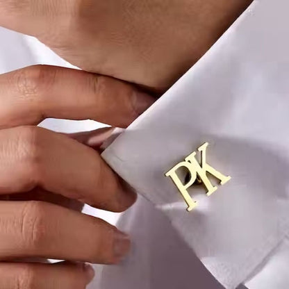 Gold cufflinks with initials 'PK' on a white shirt cuff.