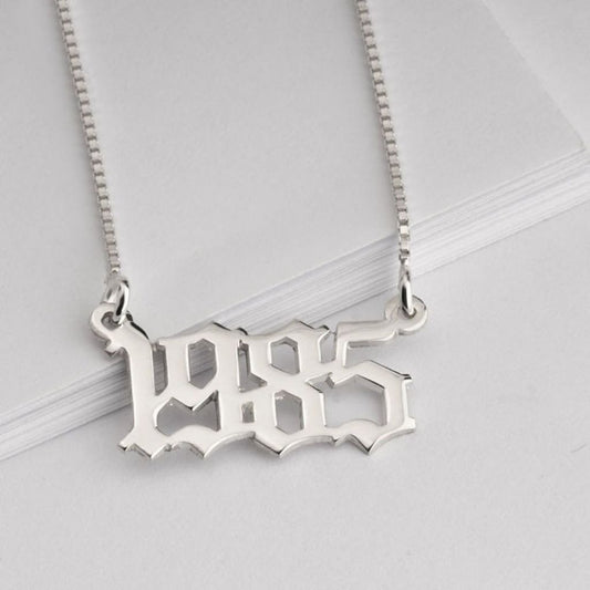 Silver necklace with '1985' design on a light gray background