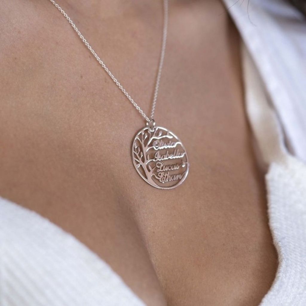 Silver necklace with a tree-shaped pendant on a person wearing a white top.