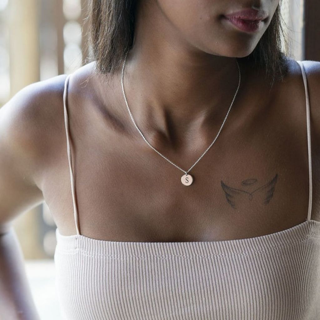 Woman wearing a necklace with a small pendant, standing indoors.
