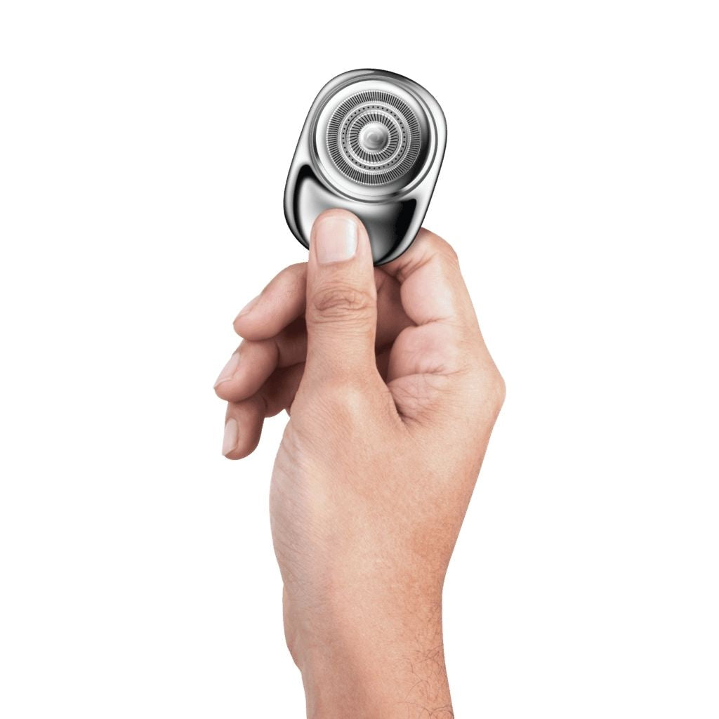 Hand holding a silver electric shaver against a white background