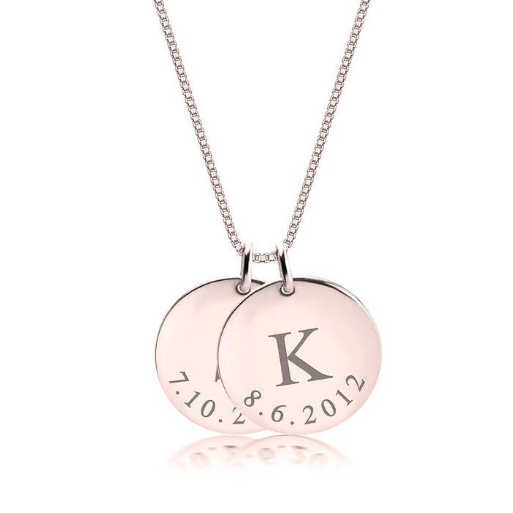 Necklace with two round pendants, one engraved with 'K' and the other with text, on a white background.