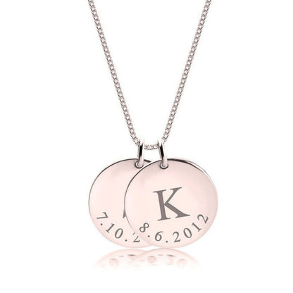 Necklace with two round pendants, one engraved with 'K' and the other with text, on a white background.