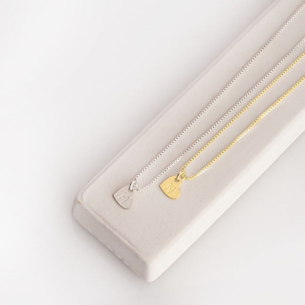 Gold necklace with a heart pendant on a white surface