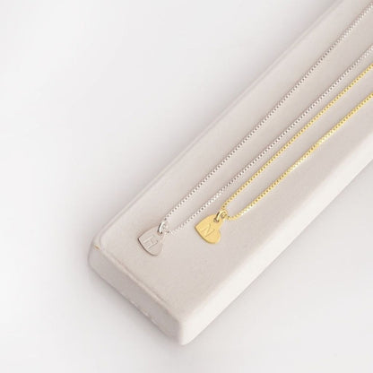 Gold necklace with a heart pendant on a white surface