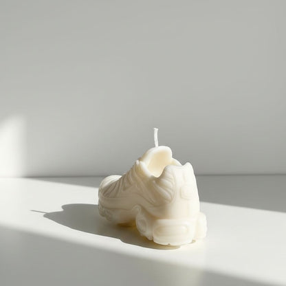 White candle shaped like a seashell on a white surface with a light gray background