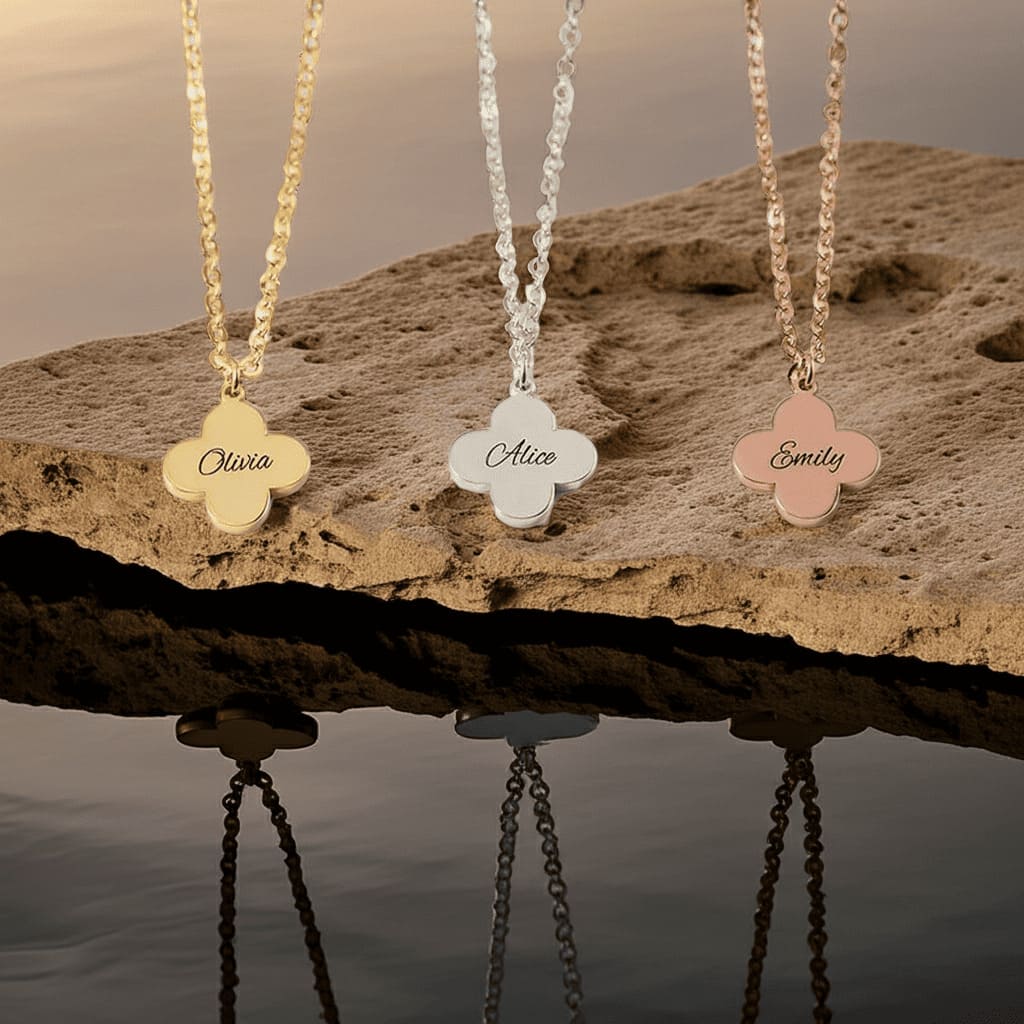 Three floral name pendants on chains against a natural background
