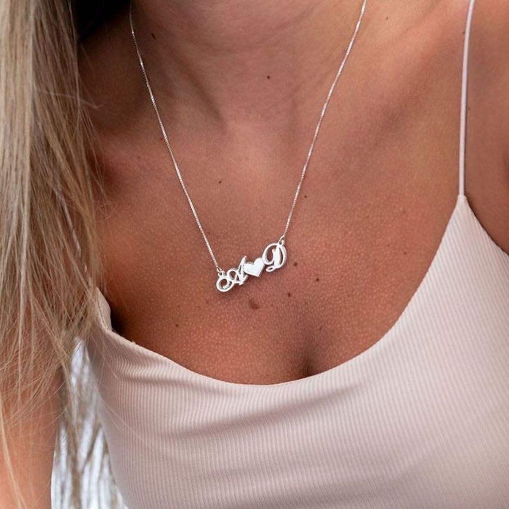Silver necklace with heart and circle pendant worn by a person in a light pink top.
