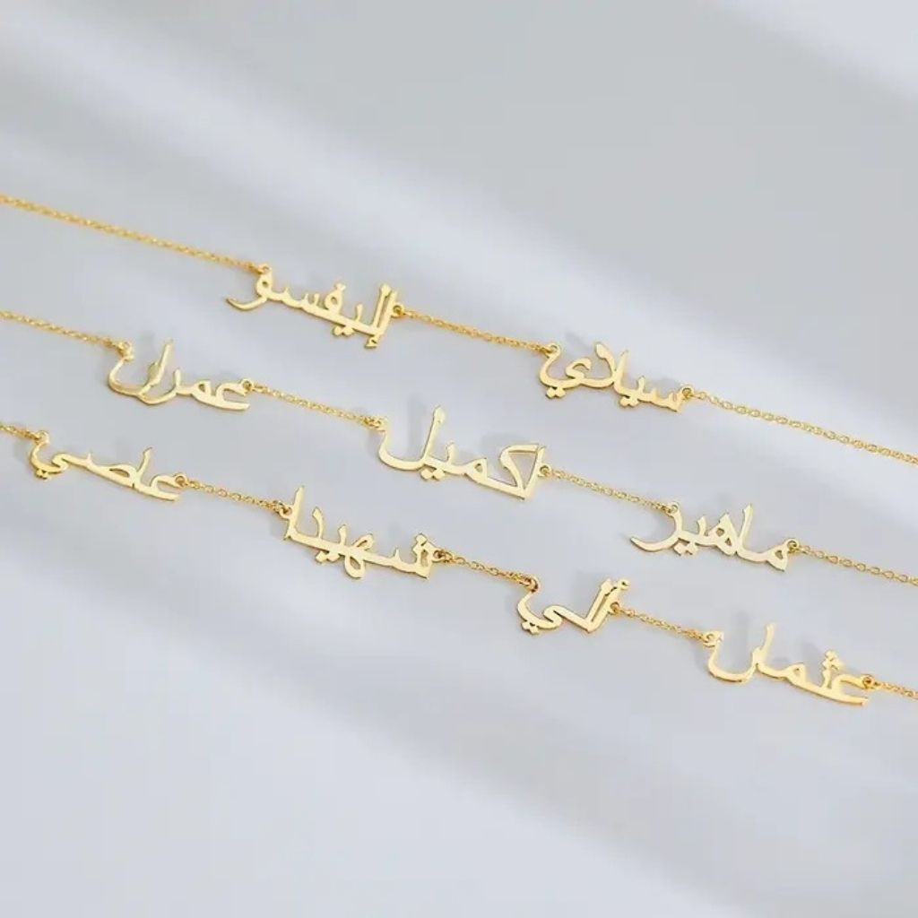 Gold necklaces with Arabic script on a light gray background