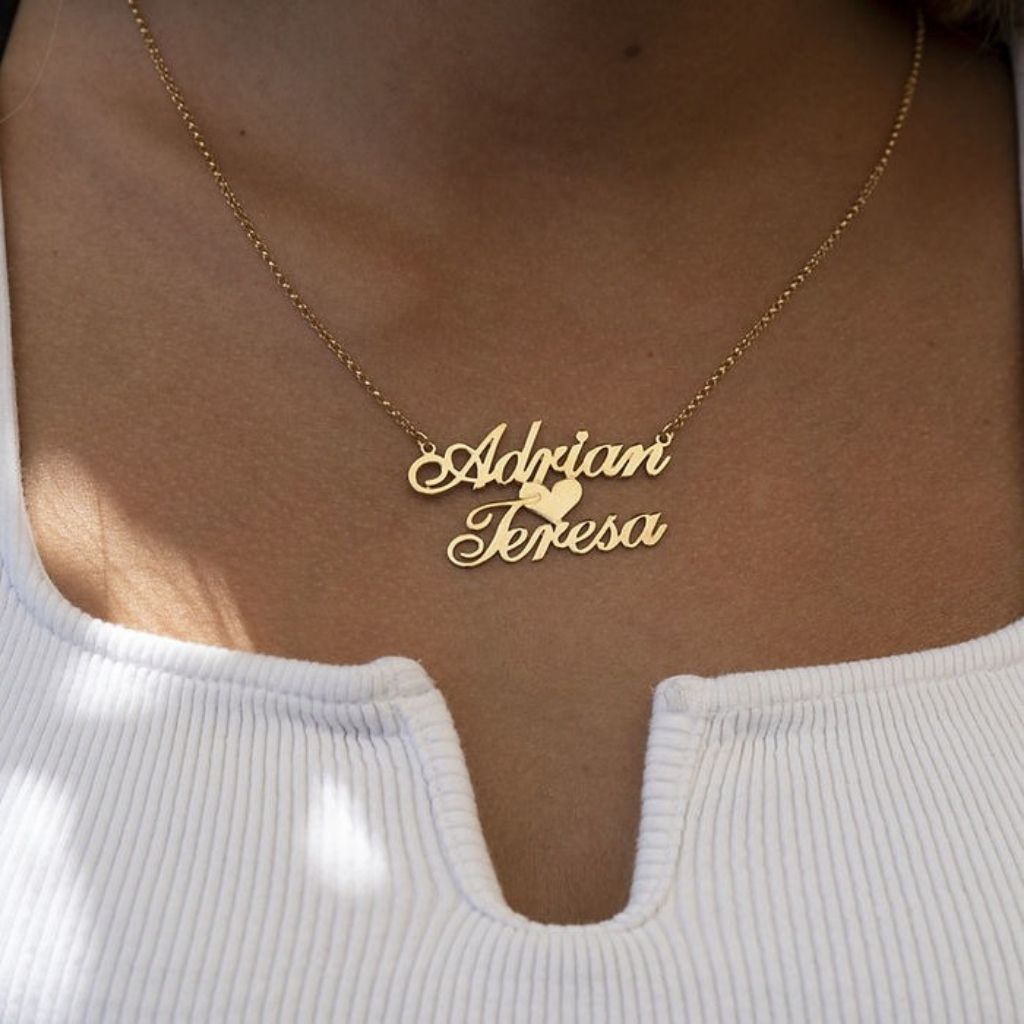 Gold necklace with 'Adrian Teresa' on a person wearing a white top.