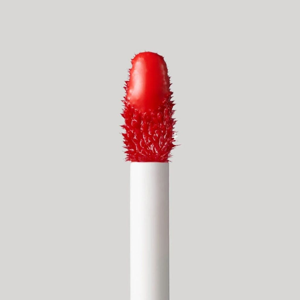 Red textured lip brush on a gray background