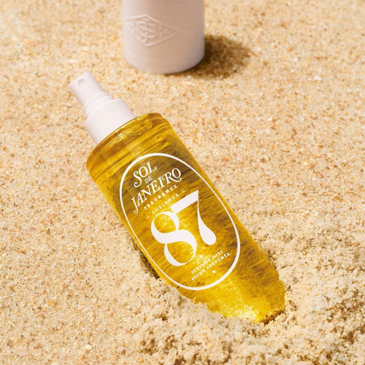 Bottle of Sol de Janeiro 87 spray on sand