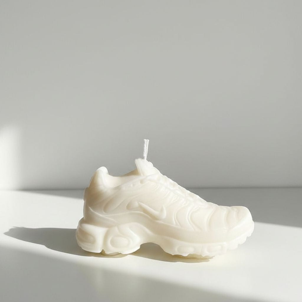 White sneaker-shaped candle on a white surface with a light gray background