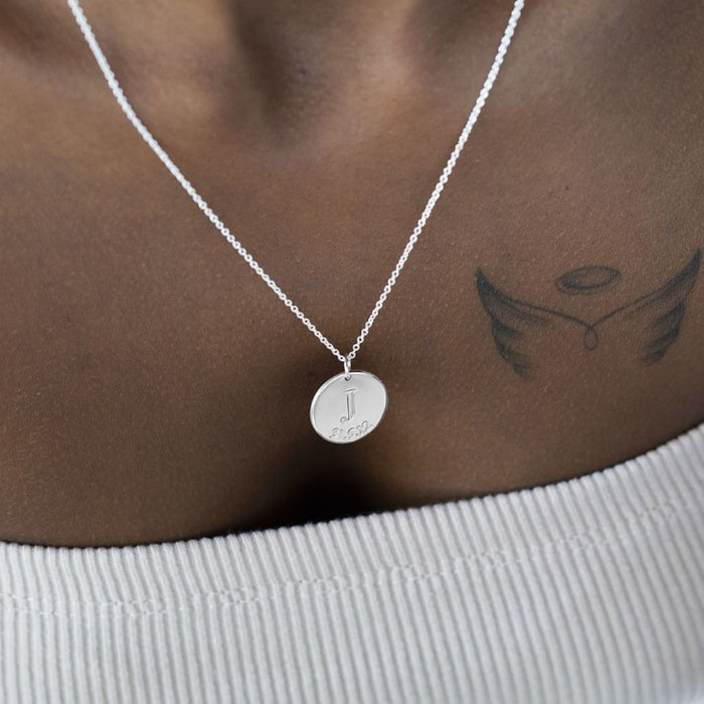 Silver necklace with a round pendant on a person's neck